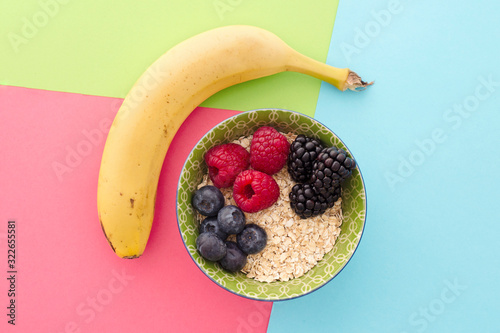 Rolled oat ball with a mix of fruits. Banana, blackberries, raspberries and blueberries and egg in very colorful background. Stylish superfood photography. Healthy breakfast