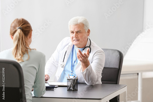 Mature male doctor working with patient in clinic