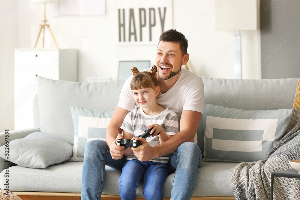 Father and his little daughter playing video games at home