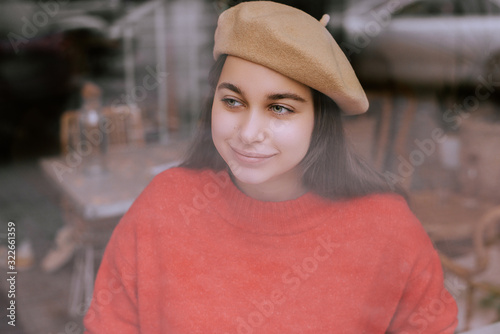 view through glass of attractive woman in beige beret 