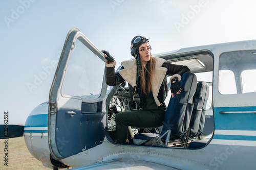 a girl in a special pilot s headdress looks out of the cockpit with a side panel