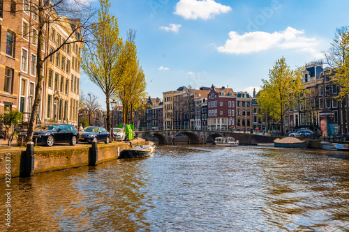 Canvas Print Stunning view of Amsterdam canals and typical dutch houses with narrow cosy streets filled with bicycles in the capital of Netherlands, Europe on a beautiful sunny day