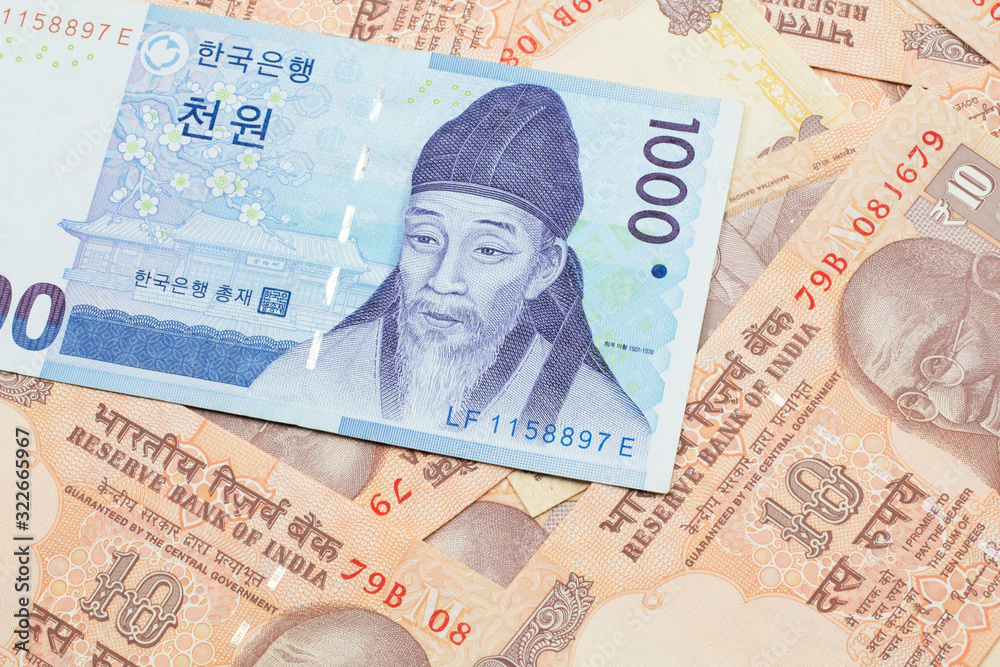 Fototapeta premium A blue South Korean one thousand won bank note close up in macro on a background of Indian ten rupee bank notes