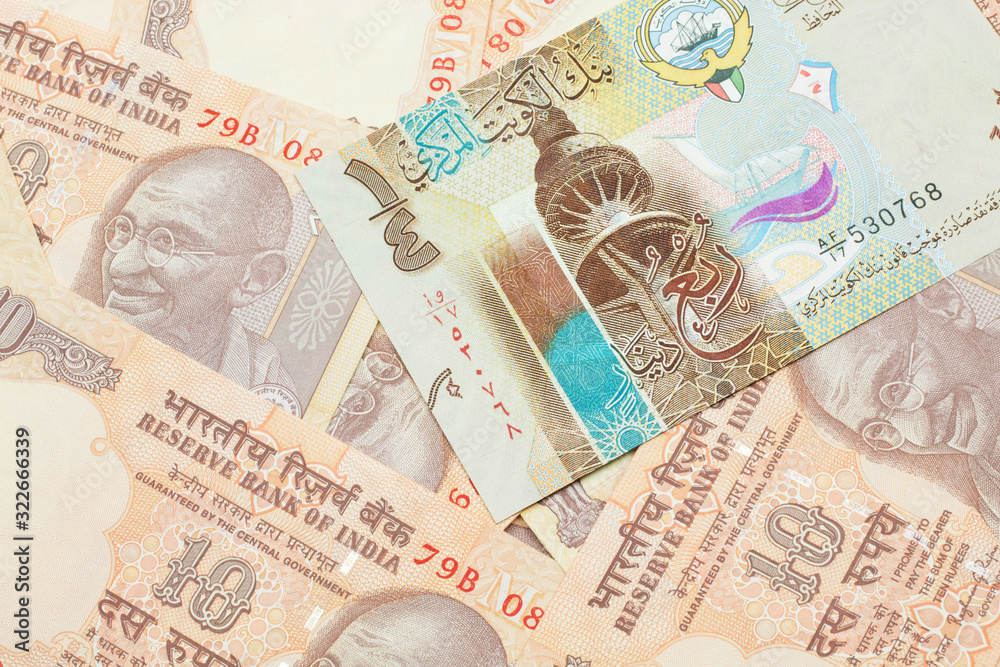 A colorful quarter dinar bank note from Kuwait close up in macro with Indian ten rupee bank notes