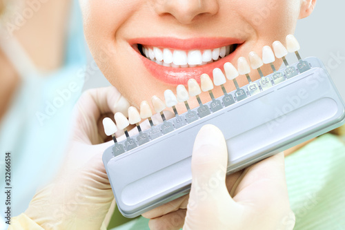 Close up portrait of Young women in dentist chair  Check and select the color of the teeth. Dentist makes the process of treatment in dental clinic office. Teeth whitenning