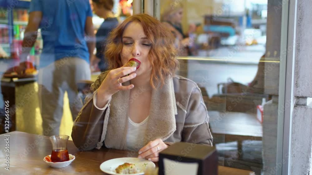 Redhead girl in the cafe eat sweets Redhead girl in the cafe eat sweets