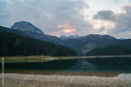 Lake in Europe with forest and mountain in the background under a beautiful sky with clouds © Artem