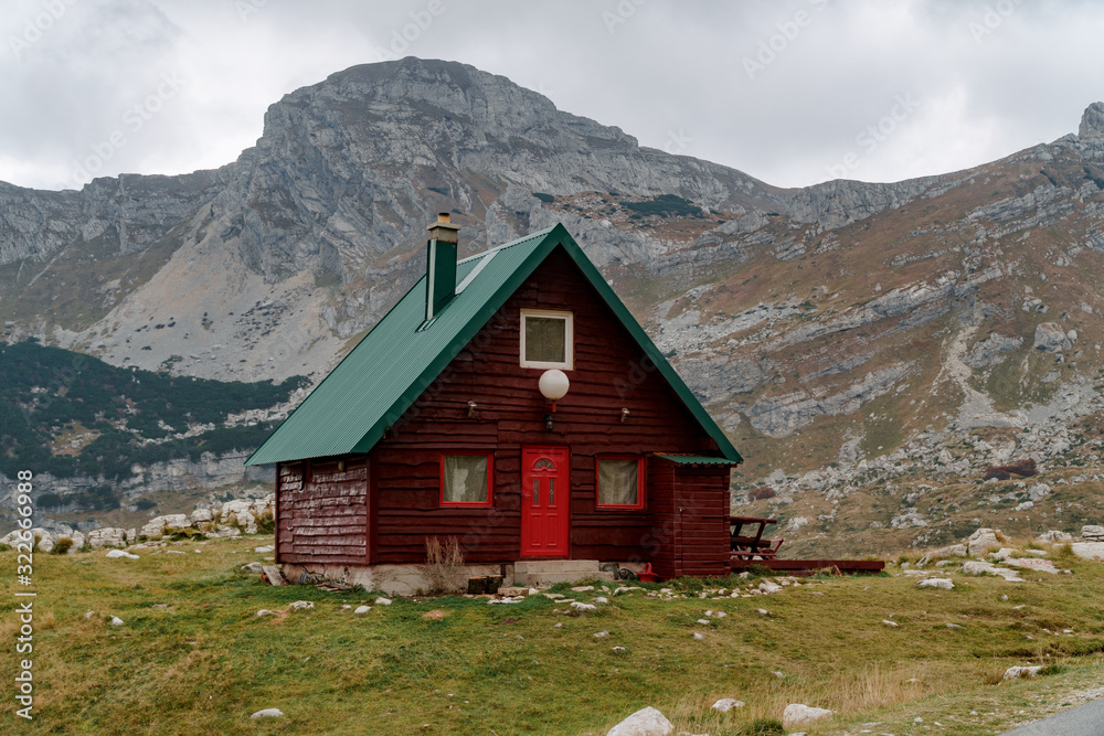 Lonely red house with a green roof in the mountains by the road. Remote places to travel.