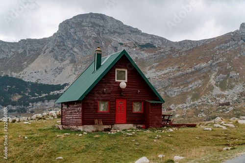 Lonely red house with a green roof in the mountains by the road. Remote places to travel. © Artem