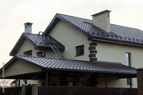 facade of a private house with windows on a gray wall under a brown tiled roof