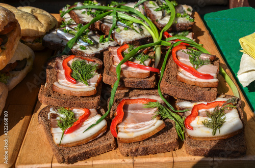 Ukrainian traditional food - salo. Sliced bacon with dark bread, pepper and onions on a wooden board