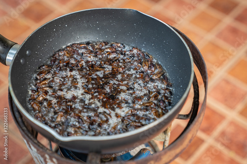 Southeast Asia, Thailand fried crickets are cooked by oil in the pan with outdoor portable picnic gas stoveat.