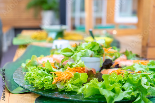 Mixed salad and vegetable roll are arranged on glass dish with sauce beside. photo