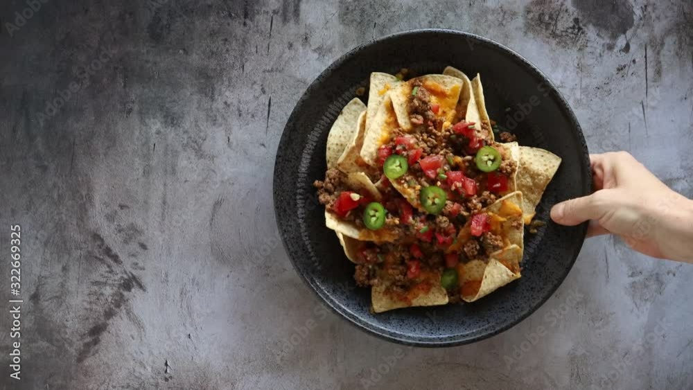 Serving a Plate of Nachos with Meat, Cheese, Salsa, and Jalapeños Serving a Plate of Nachos with Meat, Cheese, Salsa, and Jalapeños