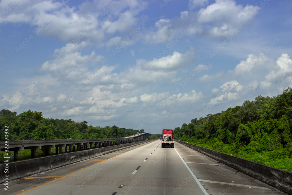 The road, a long bridge on which cars ride on a sunny summer day. Summer on the roads of Louisiana, USA