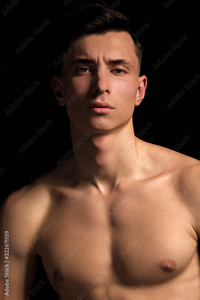 Handsome wet sport sexy stripped guy portrait with waterdrops and smoke on isolated black background