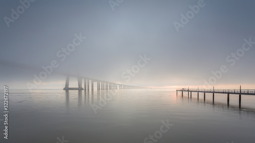 Vasco da Gama Bridge and pier over Tagus River in Lisbon  Portugal  at sunrise with a dense fog.