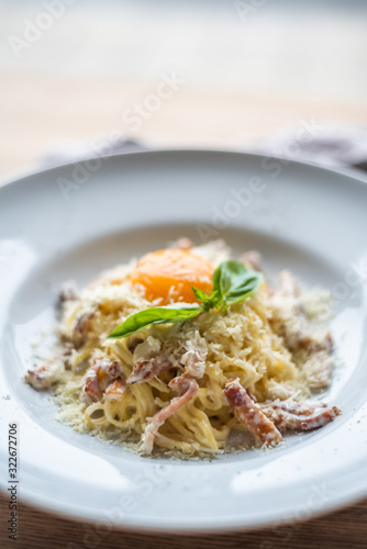 Spaghetti carbonara with pancetta, eggs and cheese in white bowl on the wooden table