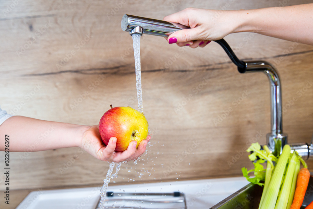 Washing apples in a child's hand. Red apple with water splash on hands ...