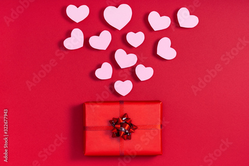 Gift box and valentine hearts on red surface. Top view, flat lay