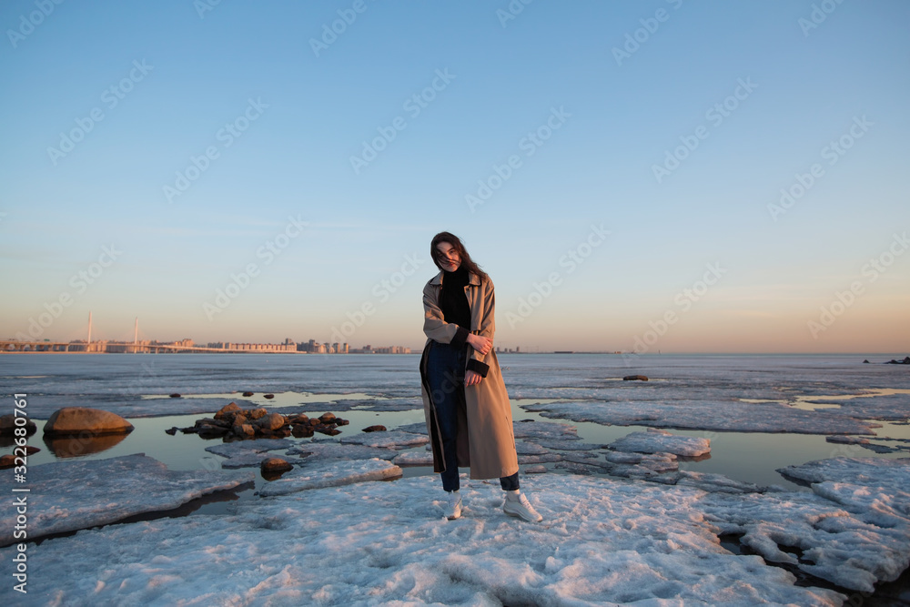 Portrait of a beautiful girl in an raincoat, winter Gulf of Finland.