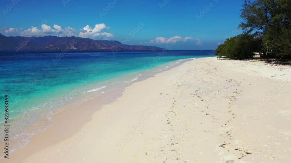 Paradise white sandy beach of tropical island washed by calm clear water of blue turquoise sea, bright sky with clouds over mountains, Bali Paradise white sandy beach of tropical island washed by calm clear water of blue turquoise sea, bright sky with clouds over mountains, Bali