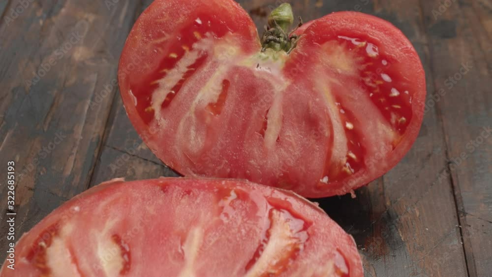 Close-up shot of female hand cutting big juicy tomato on wooden table. Ripe appetizing vegetable Close-up shot of female hand cutting big juicy tomato on wooden table. Ripe appetizing vegetable