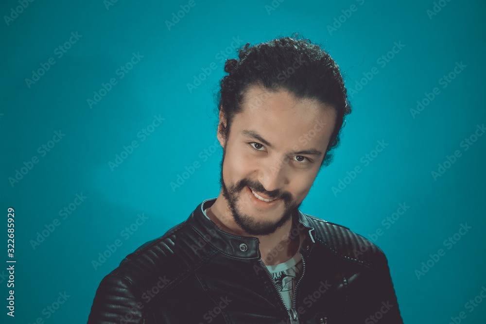 portrait of attractive Latin young in rocker jacket, Young man singing on blue background portrait of attractive Latin young in rocker jacket, Young man singing on blue background