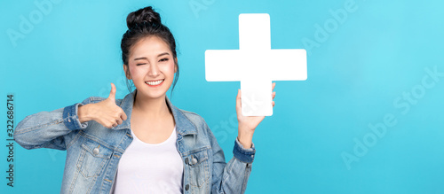 Banner of asian woman smiling, showing plus or add sign and thumb up on blue background. Cute asia girl wearing casual jeans shirt and showing join sign for increse and more benefit concept photo