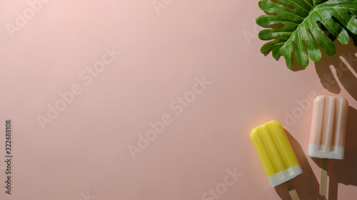 Overhead shot of strawberry and lemon flavour popsicles on pink background