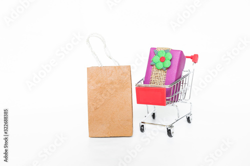 Paper shopping bag with gift in shopping cart isolate on white background, buying gift, delivery gift