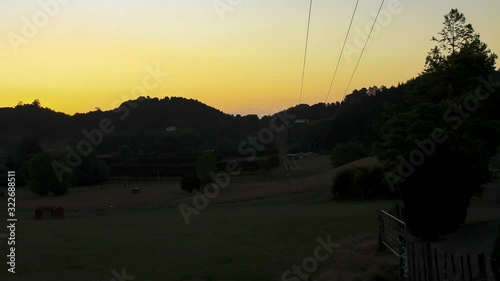 Sunset falling behind a hill in front of a field in Pataua North in New Zealand photo