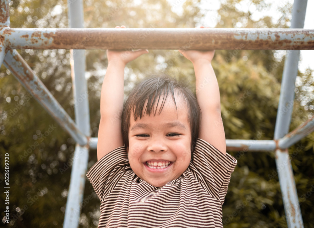 Cute Asian little girl hanging the monkey bars by her hand to exercise at out door playground on sunny day. Cute Asian little girl hanging the monkey bars by her hand to exercise at out door playground on sunny day.