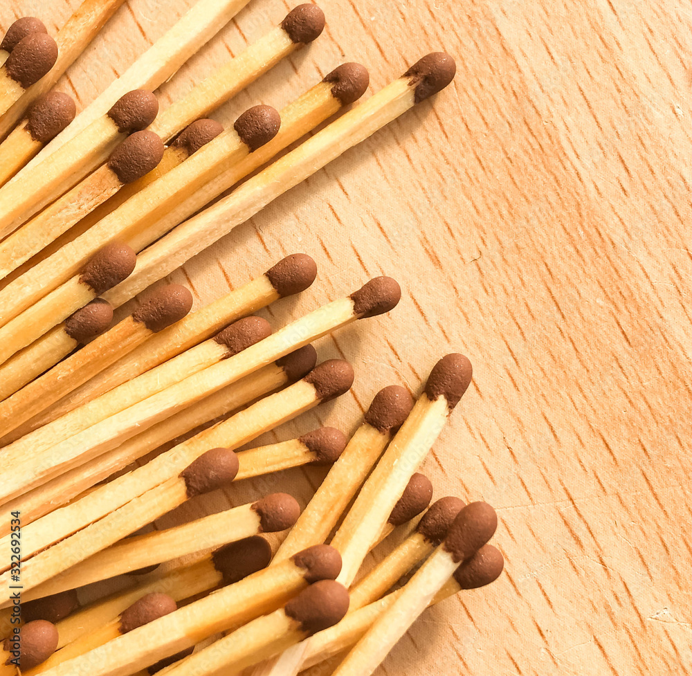 many wooden matches lie on a wooden background. flammable matches on a wooden table. many wooden matches lie on a wooden background. flammable matches on a wooden table.