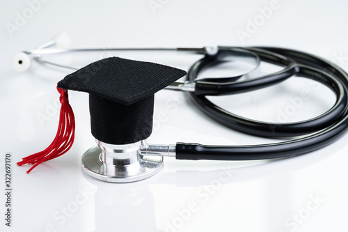 Graduation hat on doctor stethoscope, white background using as medical school, health care education or doctor's university degree concept photo