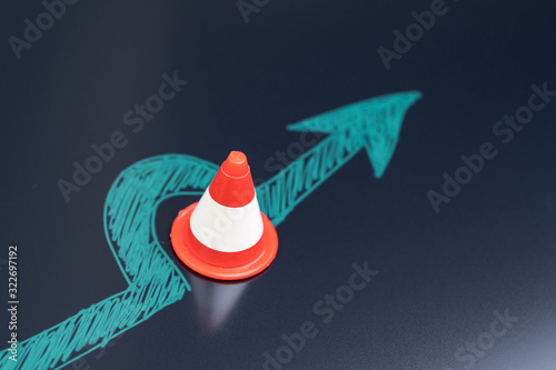 Chalk drawing arrow turn or break through road block traffic pylon on dark blackboard using as obstacle, solution for business problem or break through to success concept photo