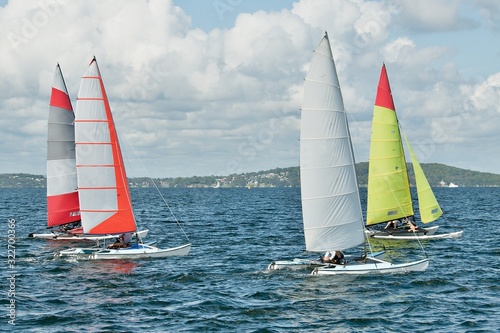 Children Sailing small catamiran sailboats with colourul sails.