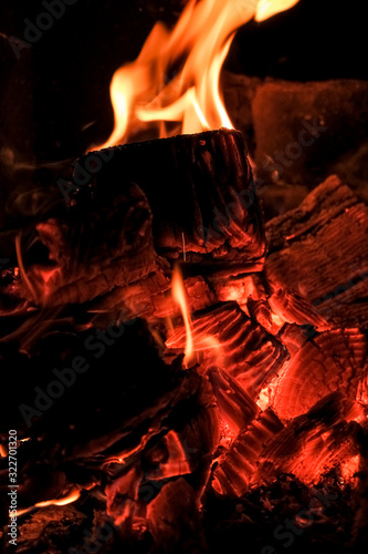 three burning billets in hot stove.Fire flame burning coal and wood in fireplace.Hot coals in the fire.Flames of a campfire in the night.Toned image