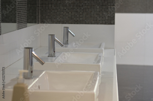 Row of white modern marble ceramic wash basin in public toilet, interior decoration design