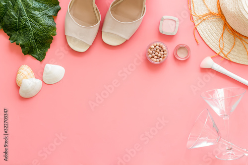 Summer female accessories. Cosmetics, clothes, shoes on pink background top-down frame copy space