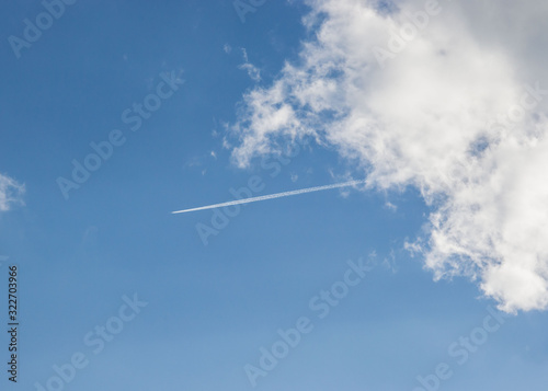 Beautiful white fluffy clouds against blue sky, natural background, plane in the sky