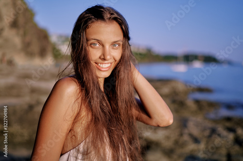 Close up outdoor portrait of young beautiful woman with long hair on the sea shore.