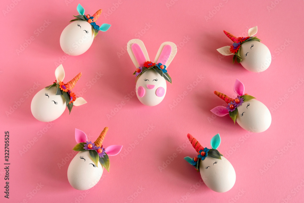top view flat lay easter eggs unicorns and rabbit on a pastel pink background