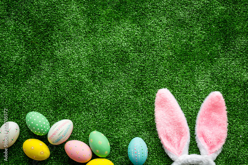 Easter concept. Eggs, Bunny's ears on green grass background top-down copy space