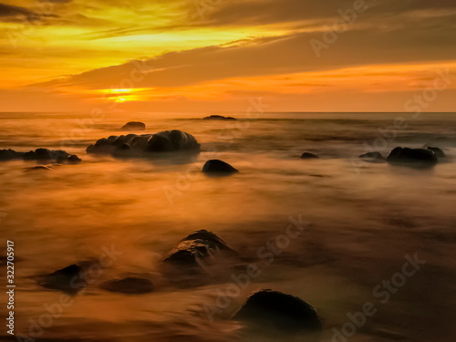 view seaside evening of many arch rocks in the sea around with silky water and yellow sun light in the sky background, sunset at Khao Lak-Lam Ru National Park, Phang Nga, southern of Thailand.