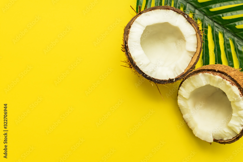 Bright tropical background with broken cocnut on palm leaf, minimal flat lay with copy space Bright tropical background with broken cocnut on palm leaf, minimal flat lay with copy space