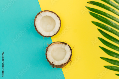 Halves of fresh raw coconut  on yellow and blue backgound. Top view, flat lay