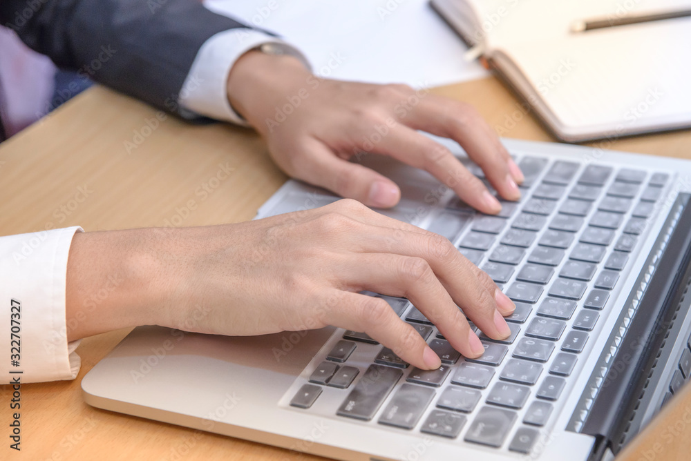 Female hand typing on laptop keyboard in office Female hand typing on laptop keyboard in office