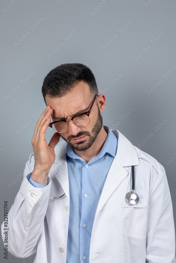 Doctor in eyeglasses suffering from a headahce Doctor in eyeglasses suffering from a headahce