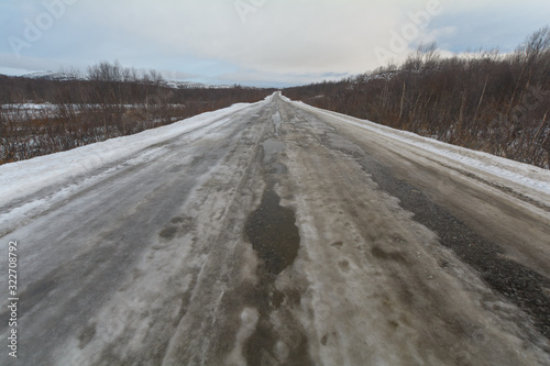 The dirt road is covered with ice .The sky is covered with clouds.